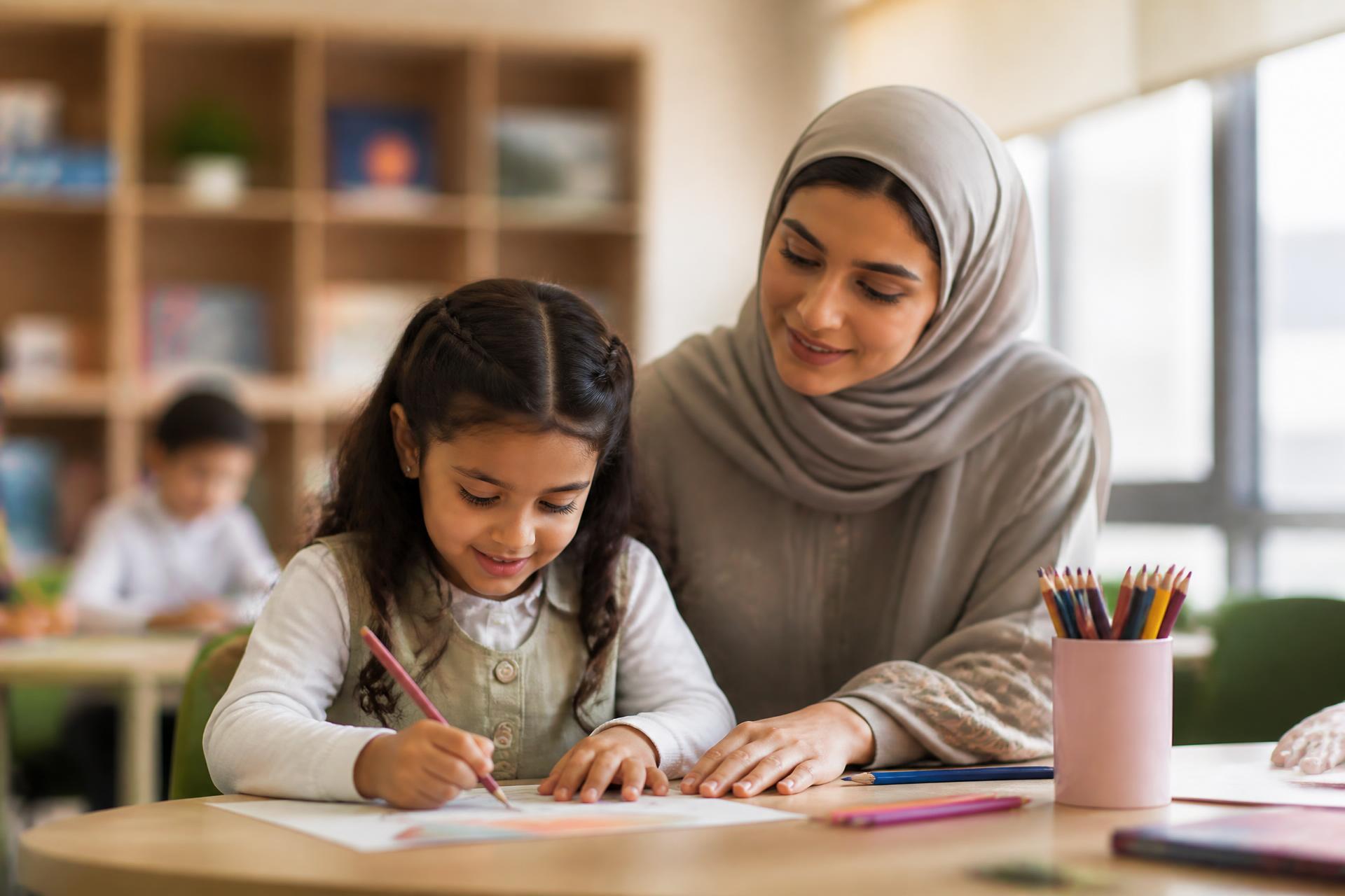معلمة تشارك طالبة في جلسة تعليمية تفاعلية داخل الفصل